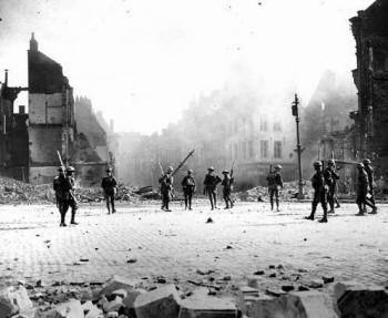 Canadese soldaten lopen door het geruïneerde Valenciennes, vlak nadat de Duitsers zijn teruggetrokken.