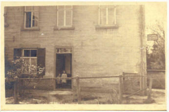 Opname van ca. 1923. Wim en Anna Bosten in de deuropenening. Rechts het uithangbord van M. Pasmans, zadelmaker/stoffeerder